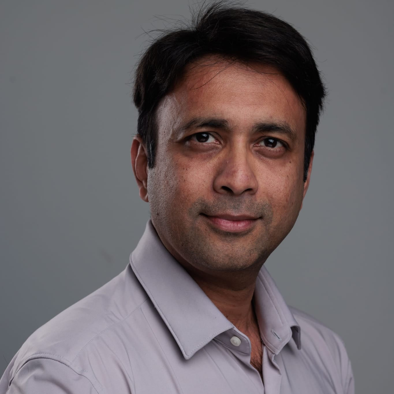 Man wearing a light gray shirt against a gray background