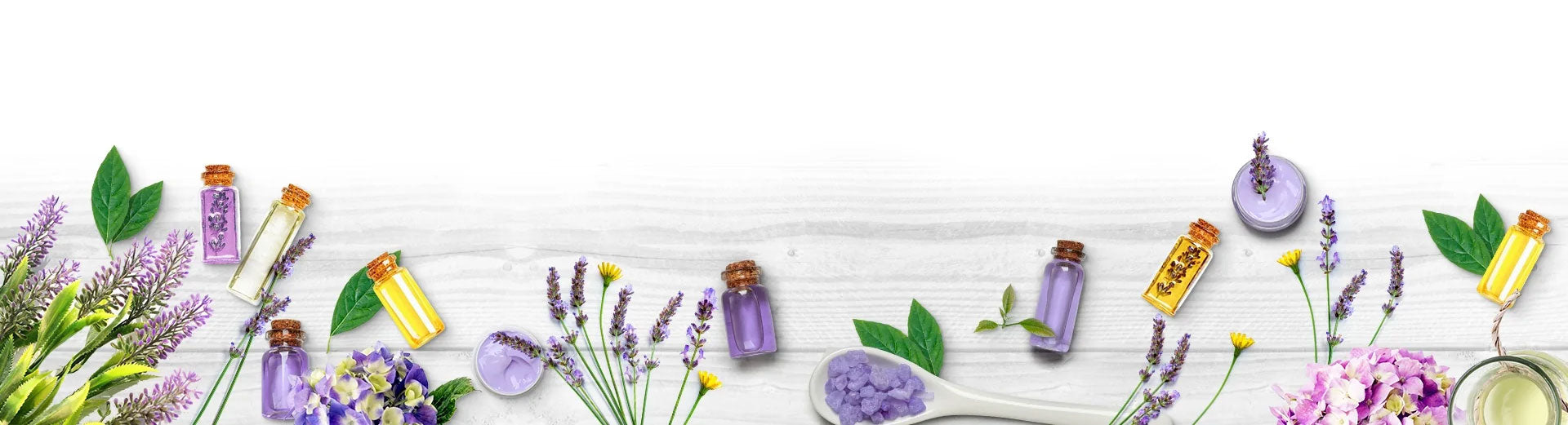 An arrangement of purple and yellow glass bottles surrounded by flowers and aromatherapy supplies